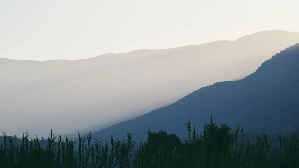 A tranquil view of mist-covered mountains at dusk, casting a peaceful ambiance.